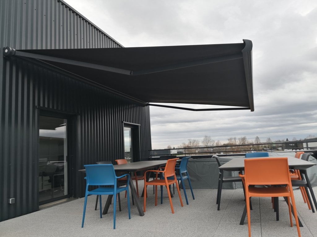 Réalisation store coffre - Store Rayy XL Largeur 592 cm x Avancée 400 cm – Coffre Coloris Gris Anthracite RAL 7016 – Toile Dickson Jais Link U787 - Pose sur bardage